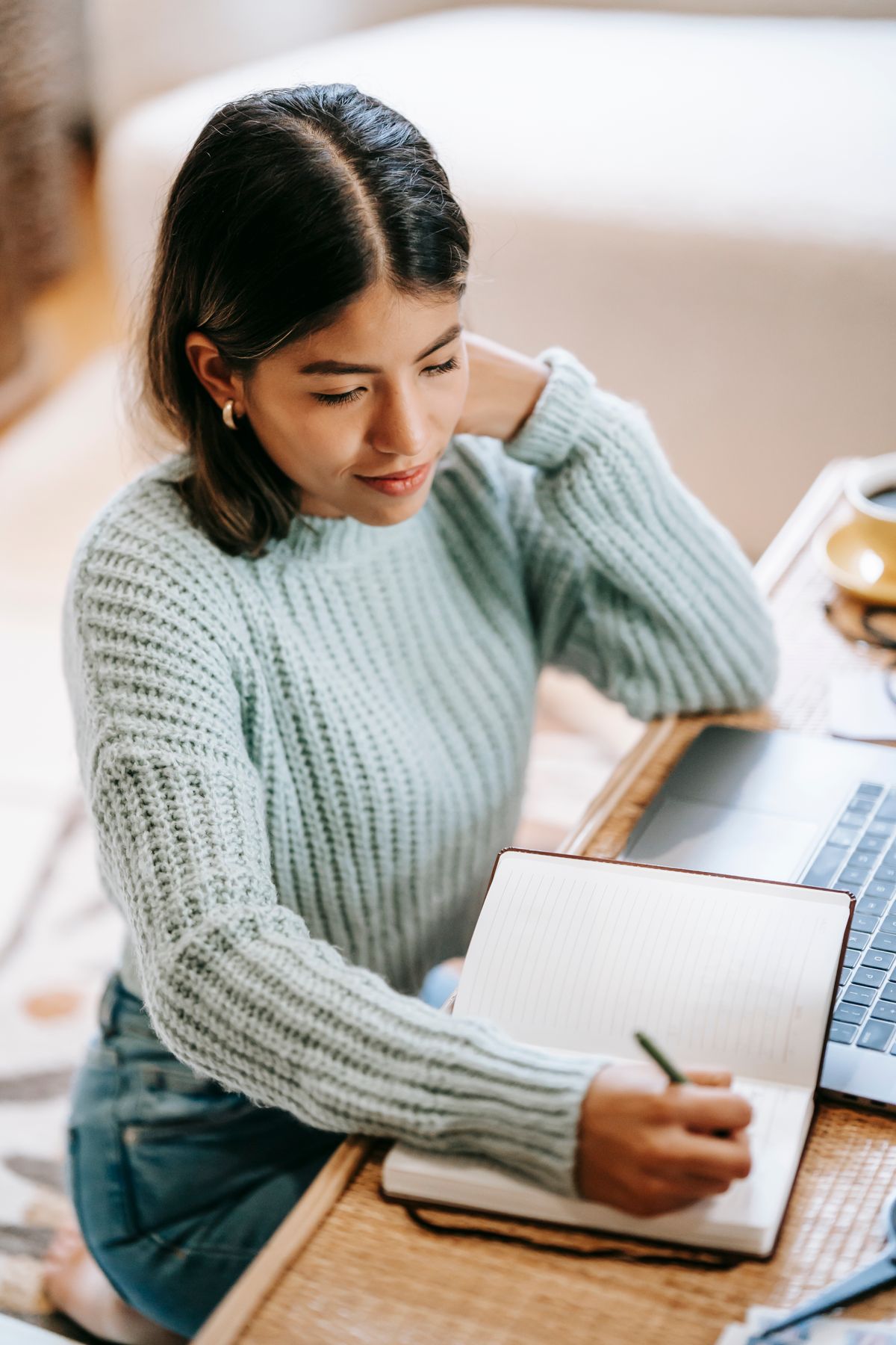 Una mujer toma notas junto a su computadora